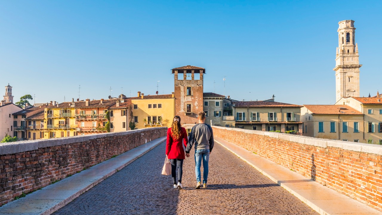 Couple walking hand in hand across a bridge