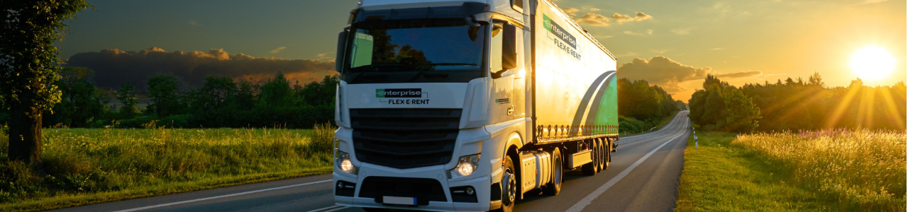 Truck driving along a road at sunset